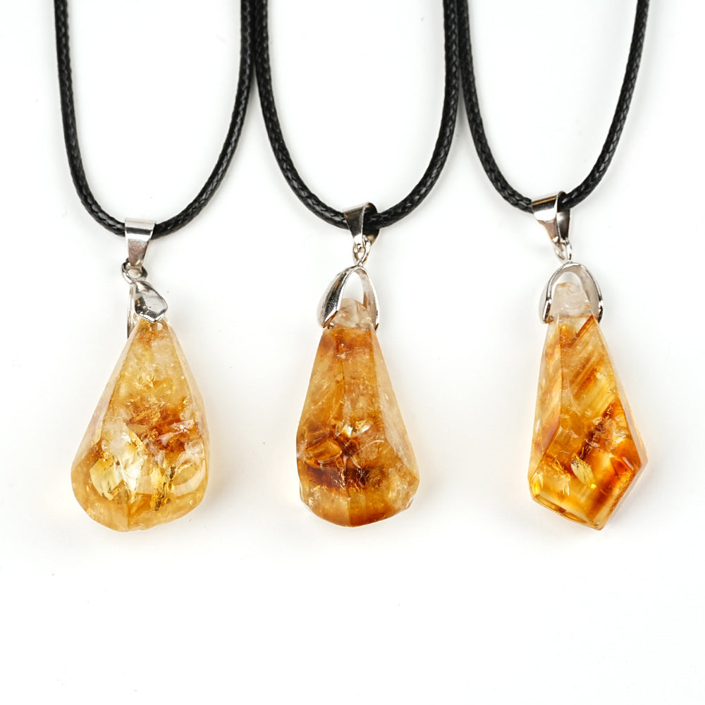 Three amber teardrop pendants on black cords against a white background