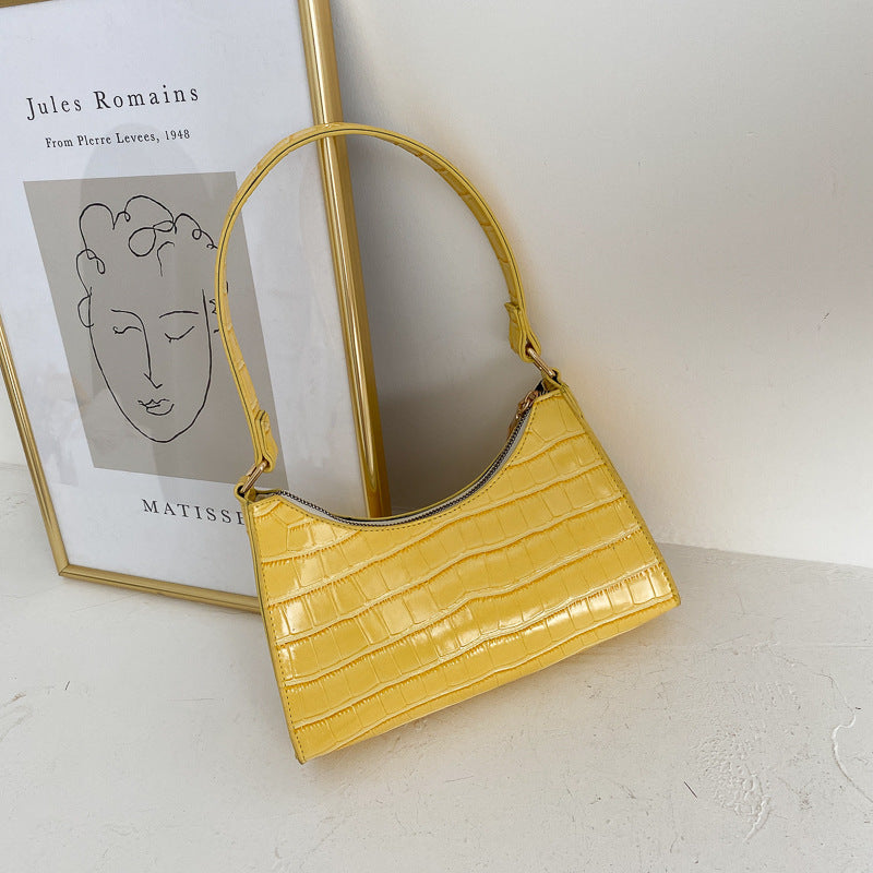 Yellow handbag on a white surface with a framed picture in the background