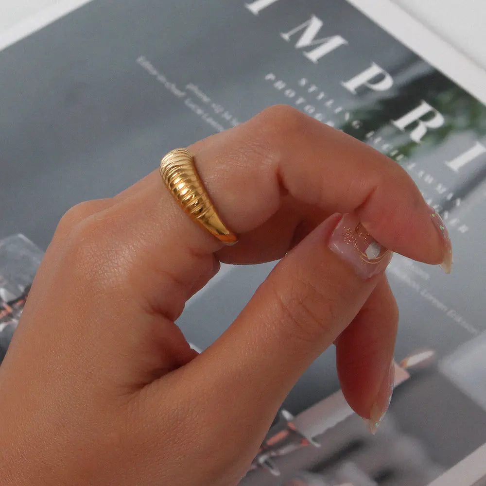Hand wearing a gold ring with a blurred magazine background