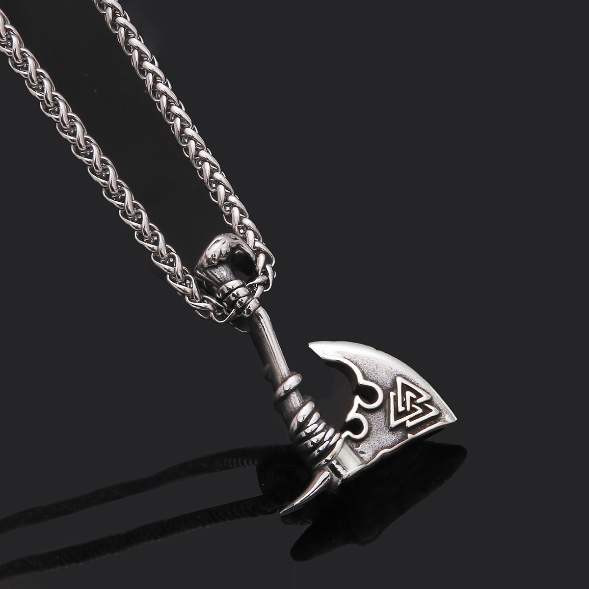 Silver axe-shaped pendant on a chain against a black background