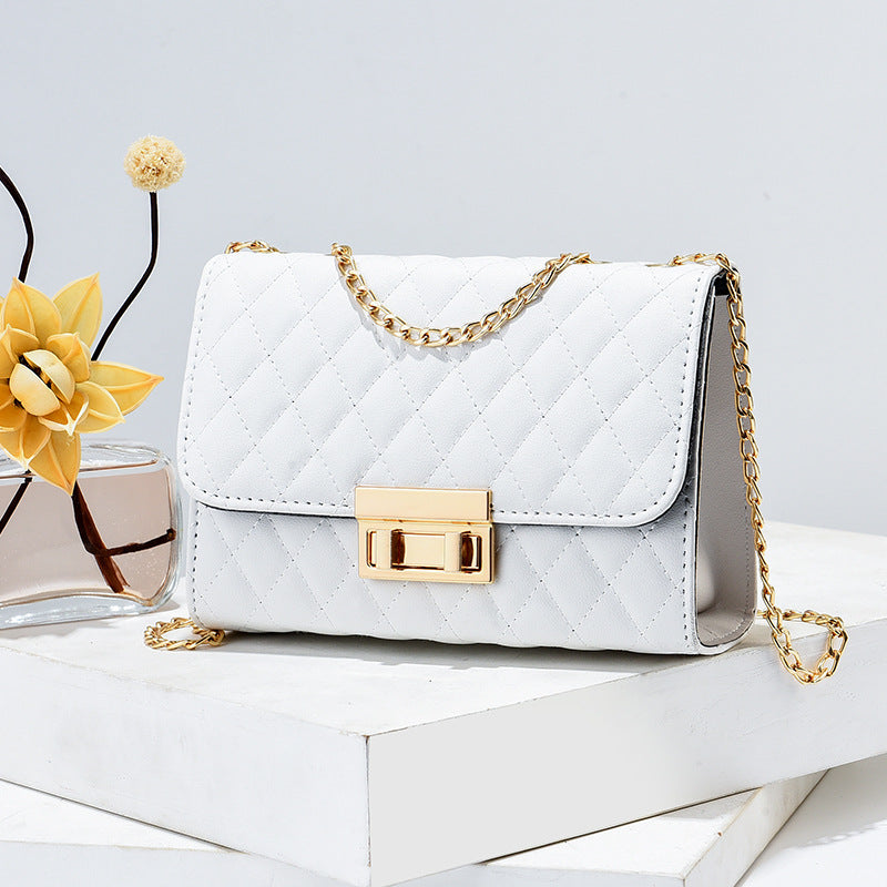 White handbag with gold chain and clasp on a light gray background