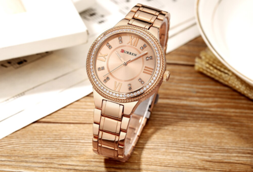 Rose gold watch with diamond accents on a wooden surface