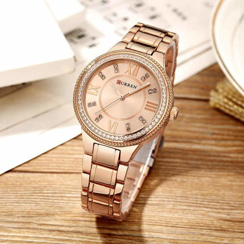 Rose gold watch with diamond accents on a wooden surface