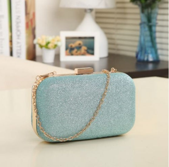 Light blue glittery clutch bag with gold chain on a beige surface