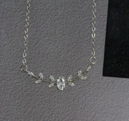 Silver necklace with floral design on a gray background