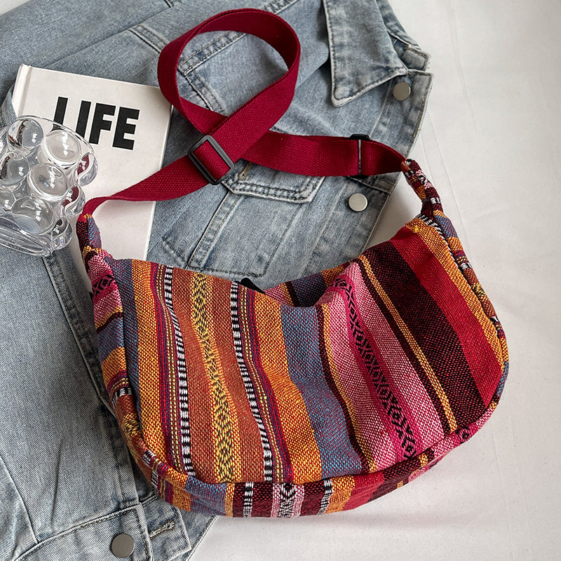 Multicolored striped bag with a red strap on a denim jacket and 'LIFE' book background