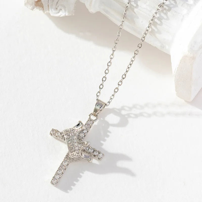 Silver cross necklace with clear stones on a white background