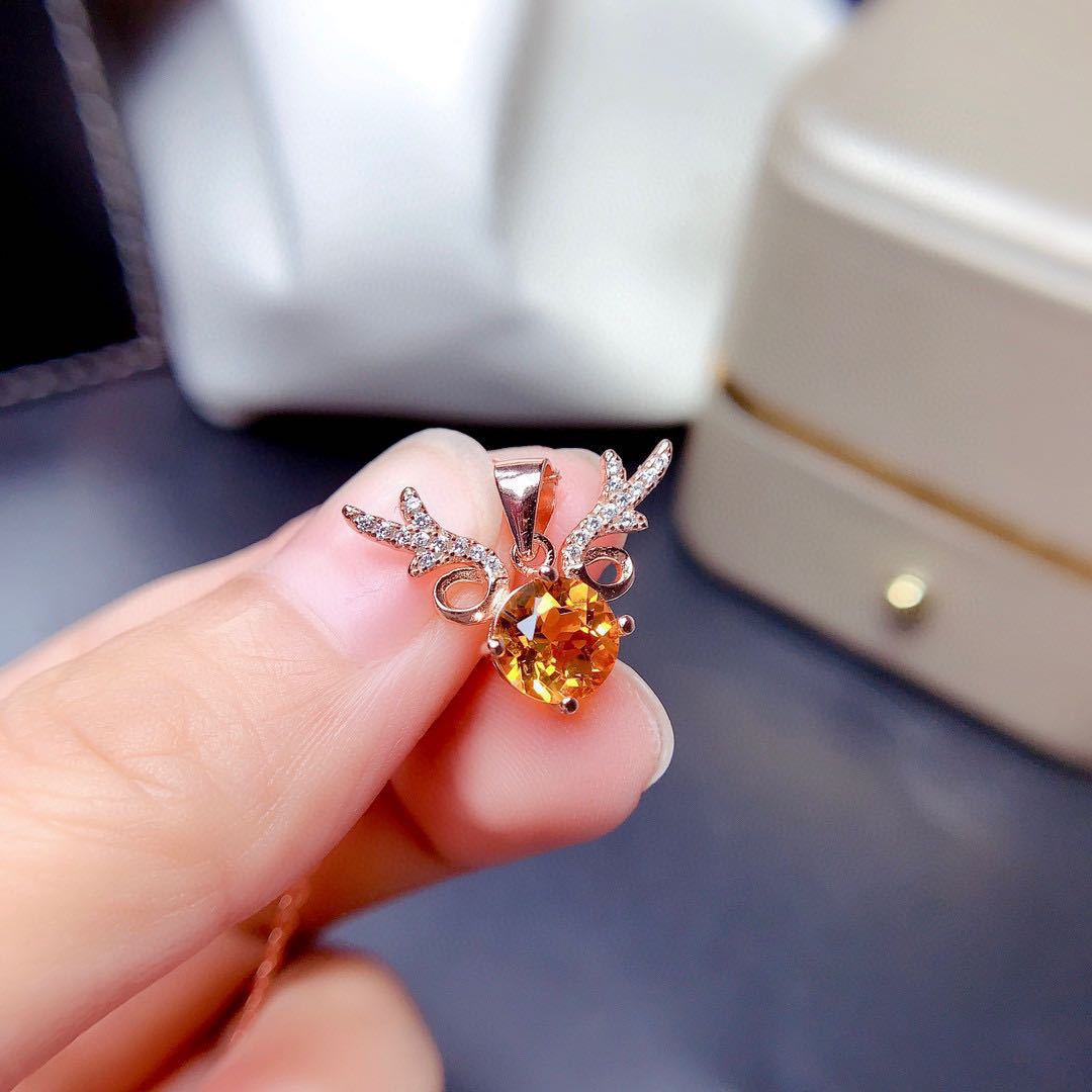 Heart-shaped gemstone earring held by a hand with a blurred background