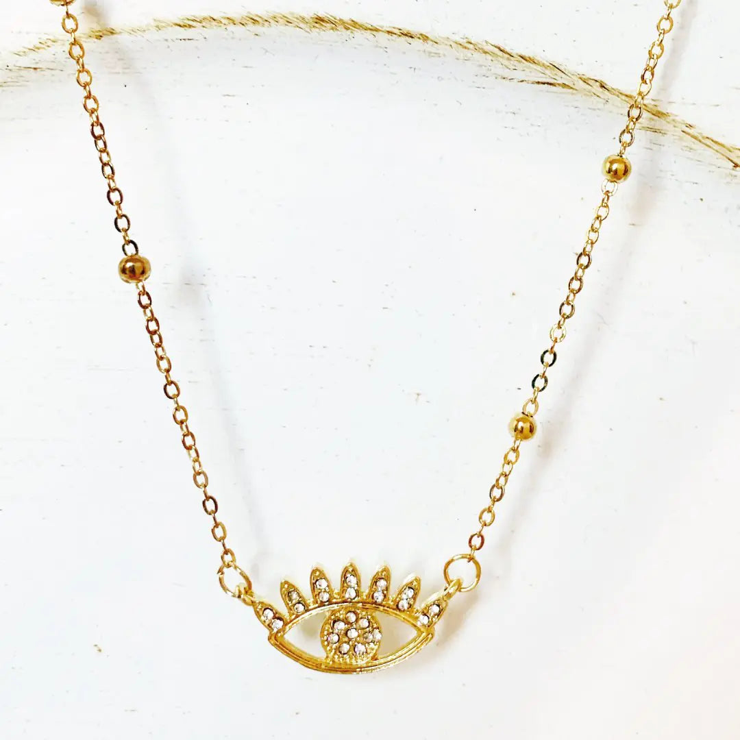 Gold necklace with an eye design on a white background