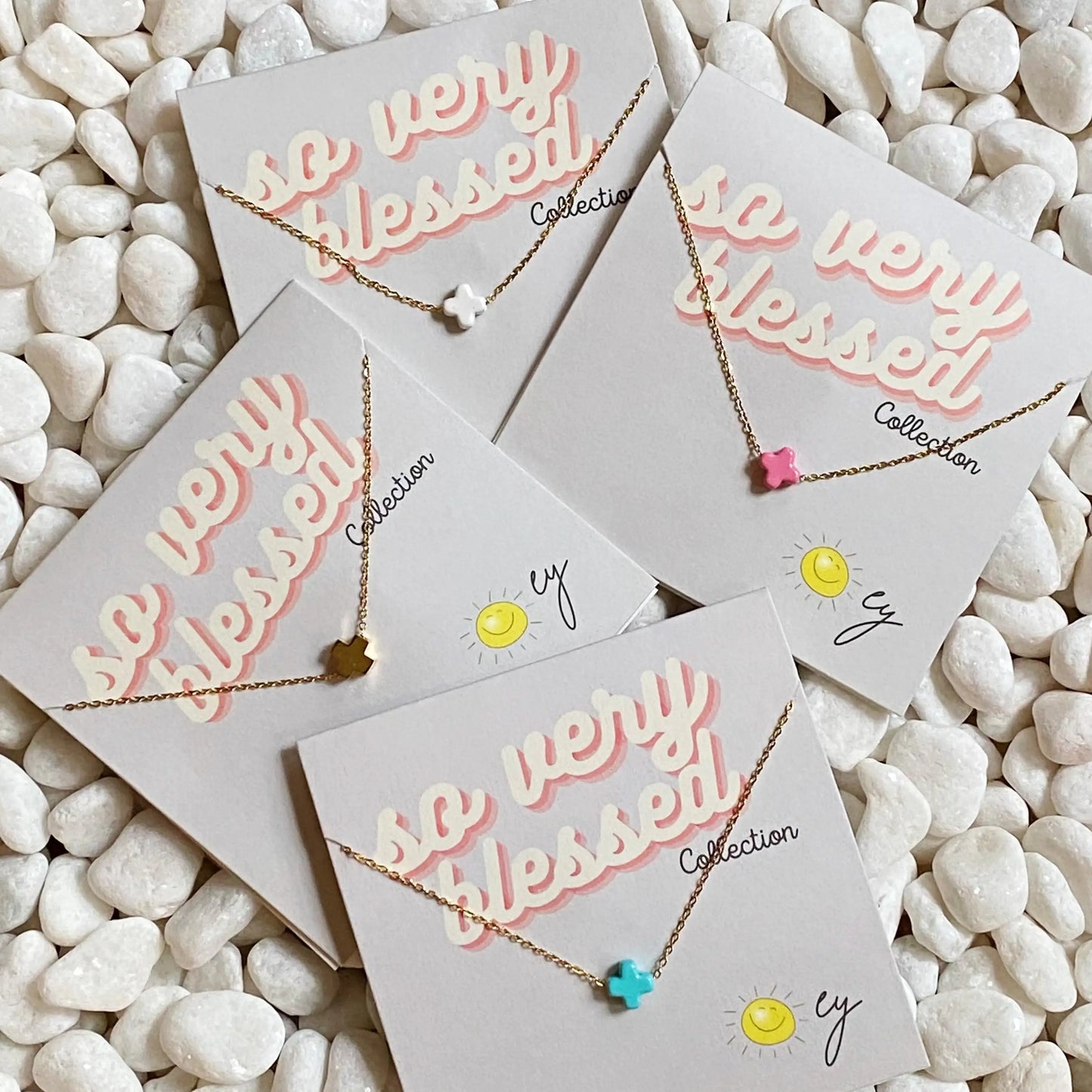 Necklaces on cards with 'so very blessed' text on a pebble background