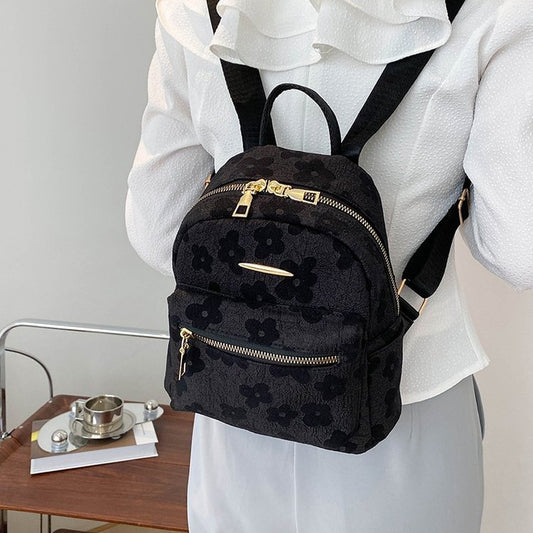 Person wearing a black floral-patterned backpack indoors.