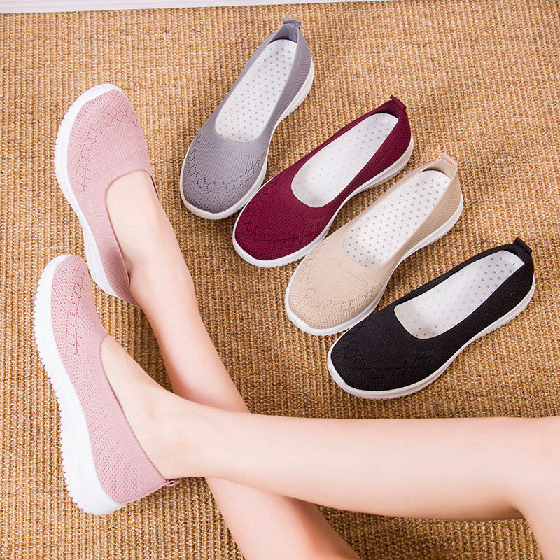 Five pairs of flat shoes in different colors on a textured surface.