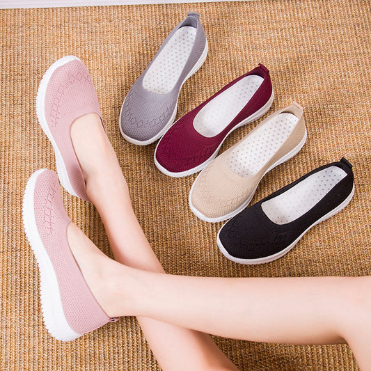 Five pairs of flat shoes in different colors on a textured surface.