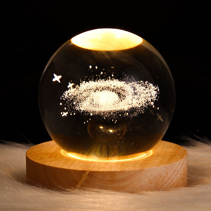 Glass sphere with galaxy inside on a wooden base against a dark background