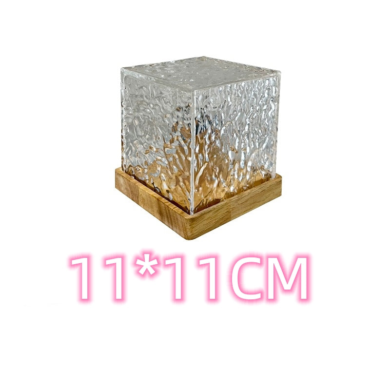 Square glass candle holder with wooden base on a white background