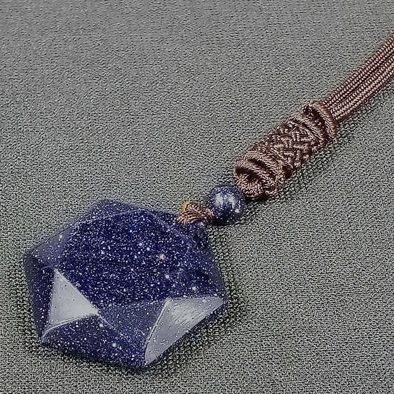 Blue stone pendant on a brown cord against a gray background