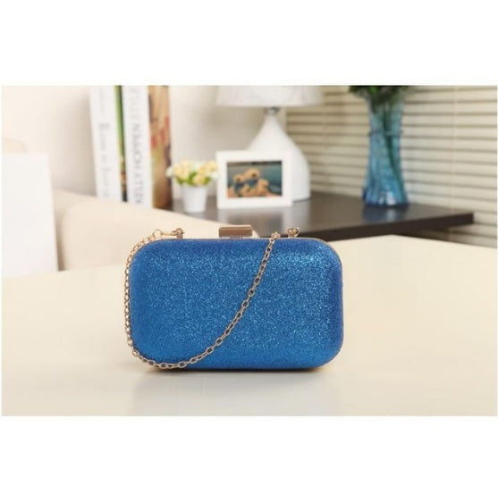 Blue glittery handbag with a chain strap on a light surface.