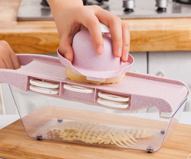 Person using a kitchen tool to slice potatoes on a wooden cutting board.