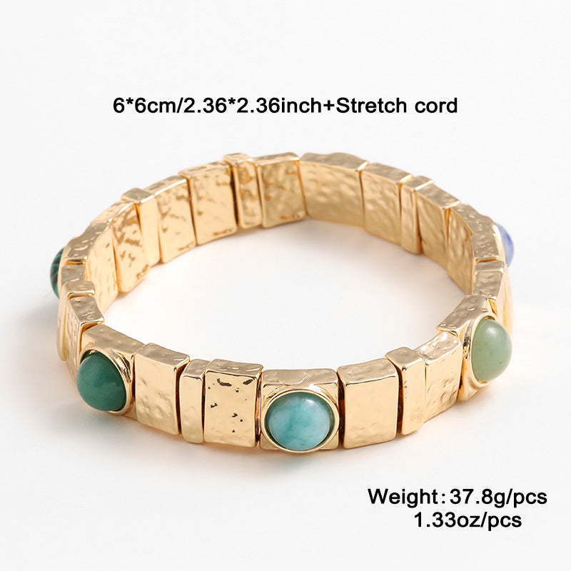 Gold bracelet with green stones on a white background