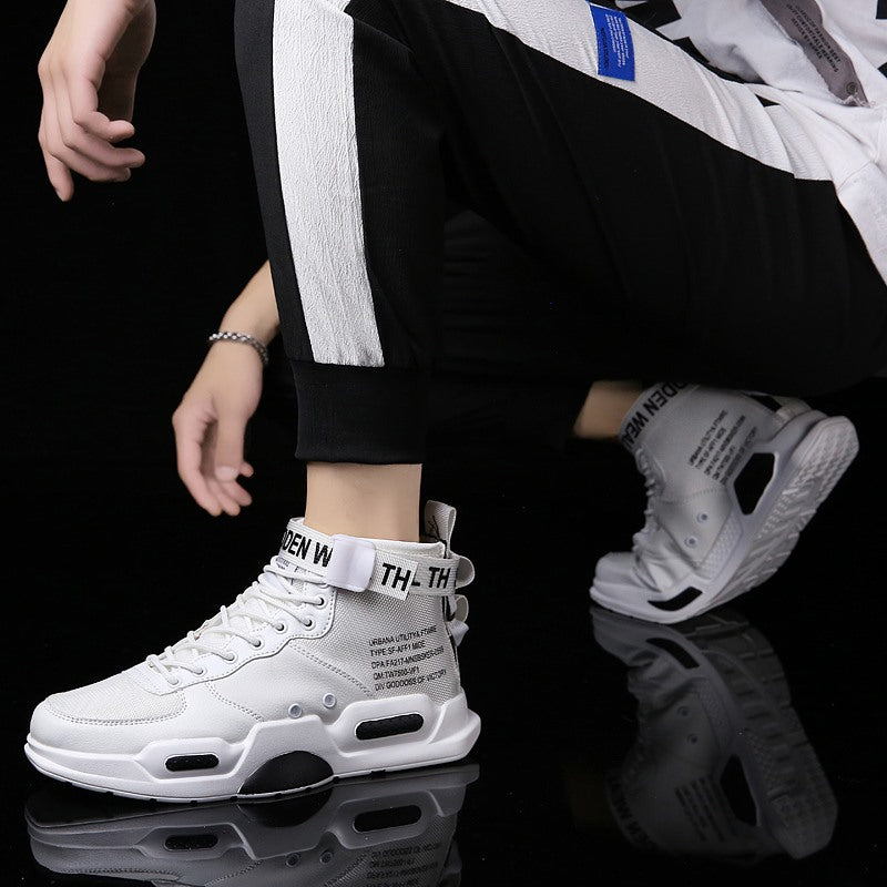 White high-top sneakers with text design worn by a person on a reflective surface.