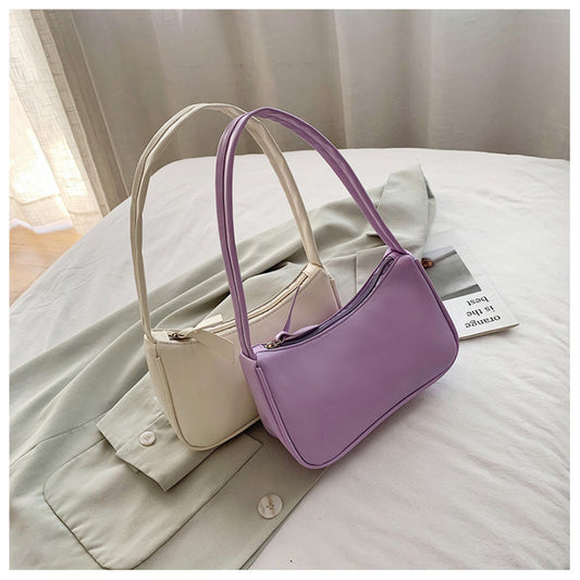 Purple handbag and beige bag on a light-colored surface with a neutral background