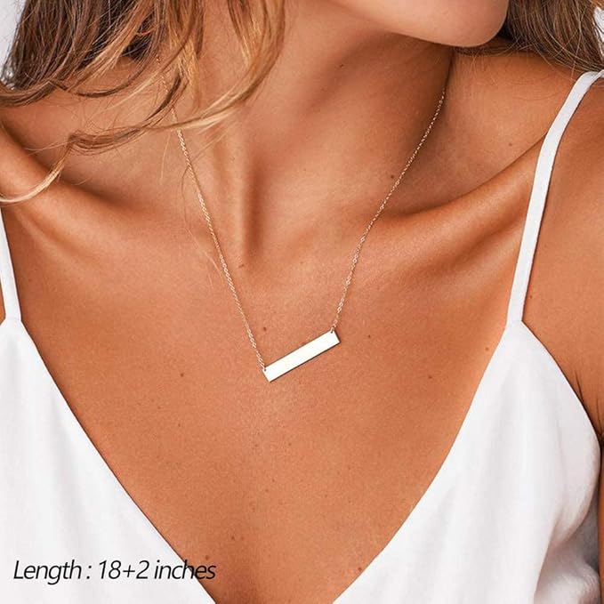 Gold necklace with a bar pendant on a person wearing a white top.