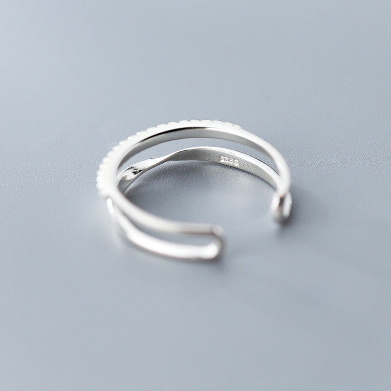 Silver open ring on a light gray background