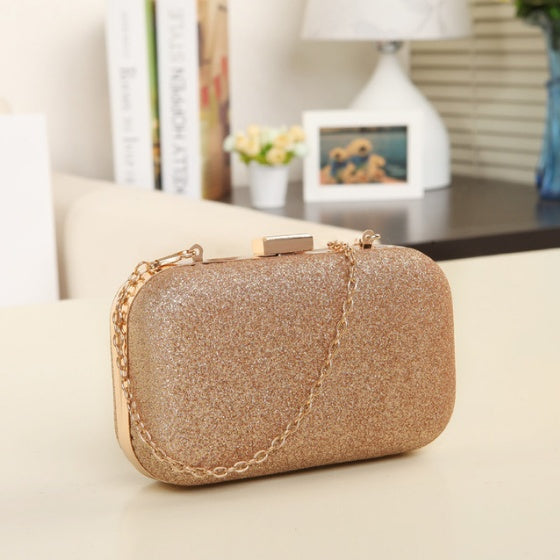 Gold glittery clutch bag on a light surface with a blurred indoor background