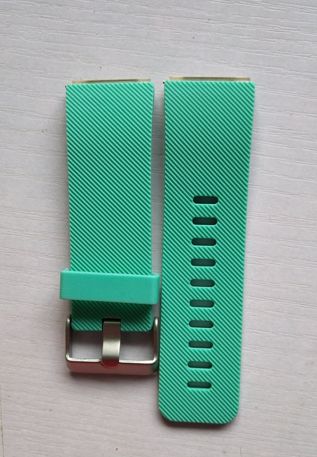 Turquoise watch strap with metal buckle on a light gray background