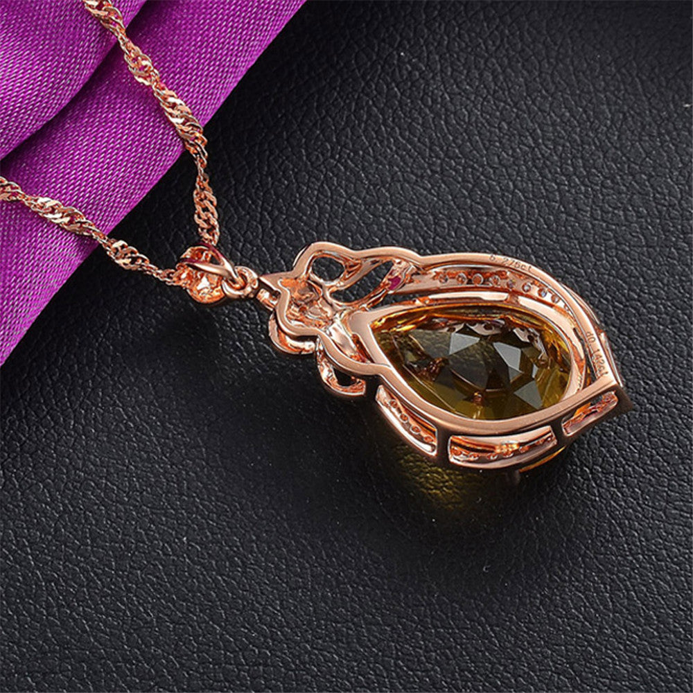 Rose gold pendant with a green gemstone on a black surface