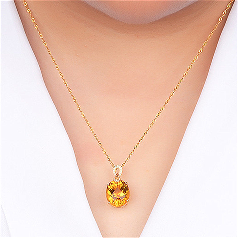 Gold necklace with a yellow gemstone pendant on a white background