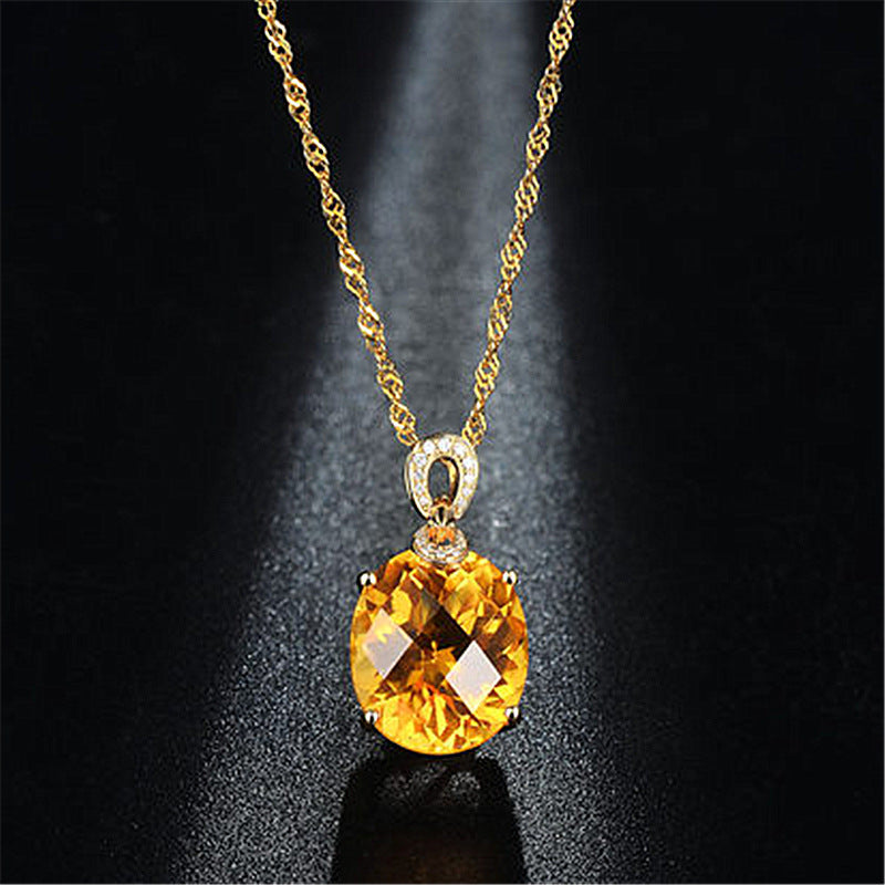 Gold necklace with a yellow gemstone pendant on a dark background
