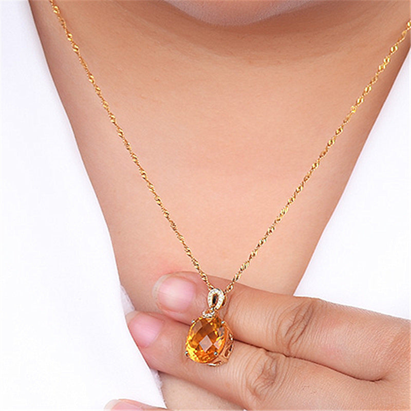 Gold necklace with a teardrop-shaped orange gemstone pendant on a white background