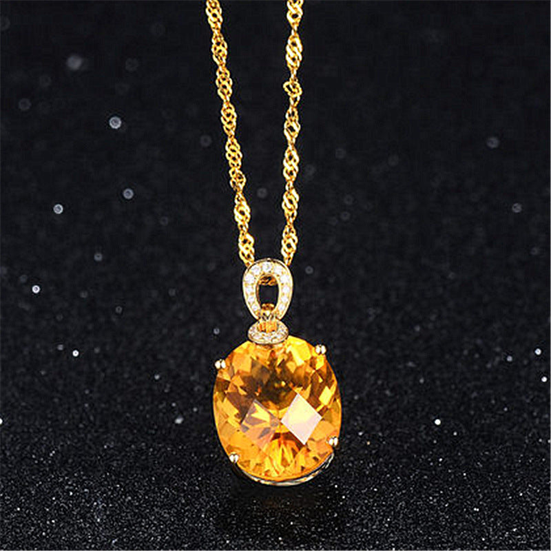 Gold necklace with a yellow gemstone pendant on a black background