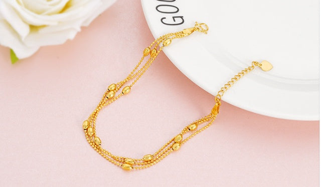 Gold bracelet on a person's wrist with a blurred background