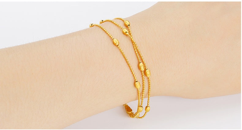 Gold bracelet on a wrist against a white background