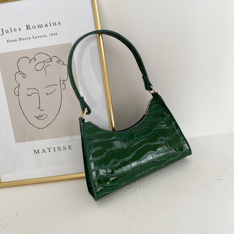 Green handbag on a white surface with a Matisse poster in the background