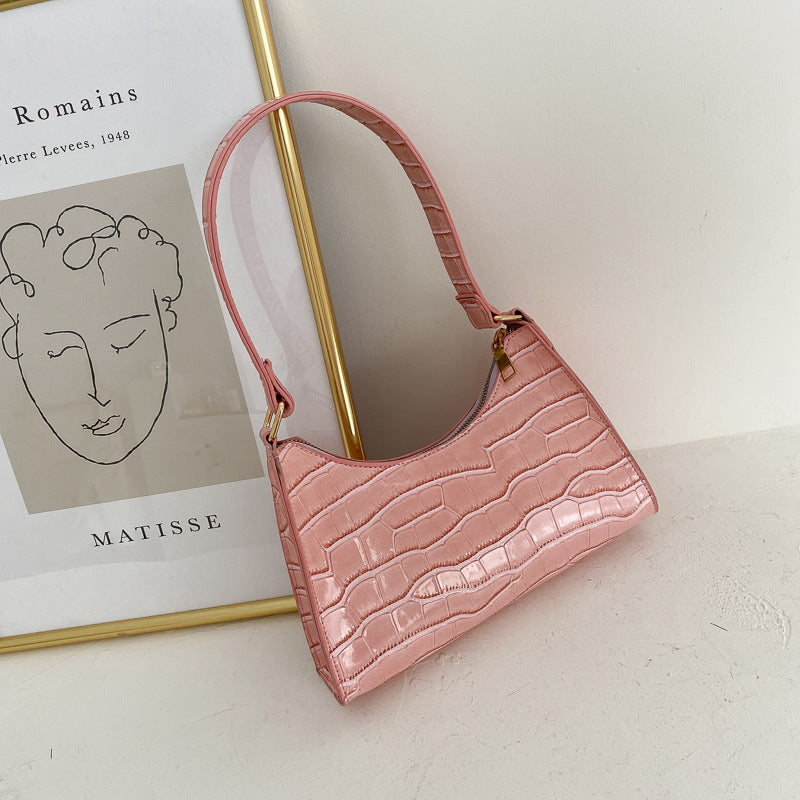 Pink textured handbag on a light surface with a Matisse book in the background