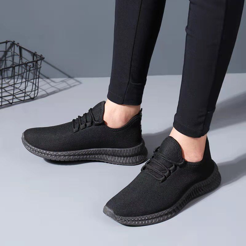 Black sneakers worn with black pants on a light gray background