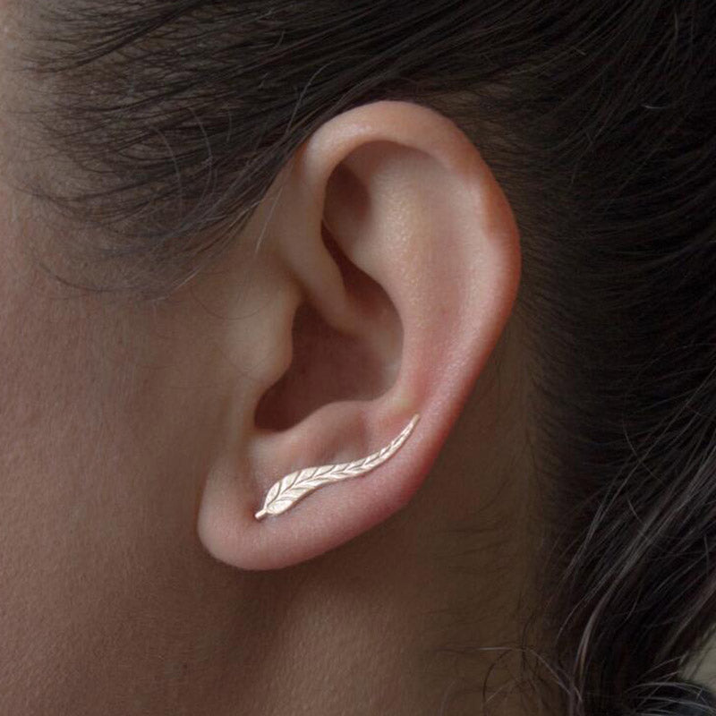 Close-up of an ear wearing a gold leaf-shaped earring.