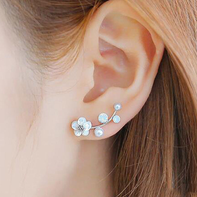 Close-up of an ear wearing a floral earring with pearls.