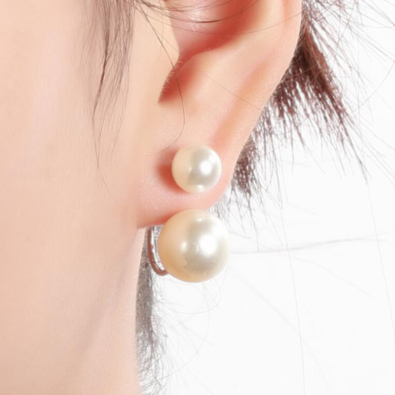 Pearl earrings being worn on an ear with a neutral background