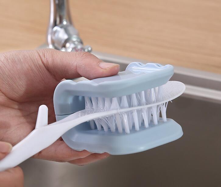 Hand holding a kitchen scrubber with a soft silicone head over a sink.