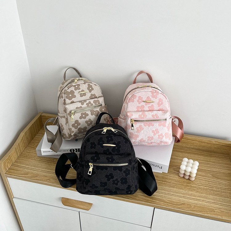 Three floral-patterned backpacks on a wooden surface with a white background