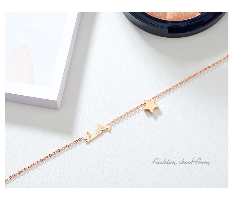 Rose gold bracelet with star and letter charms on a white surface