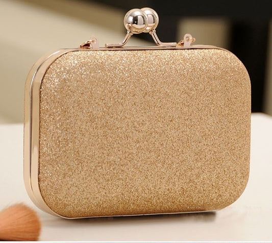 Gold glittery clutch bag with a decorative handle on a neutral background