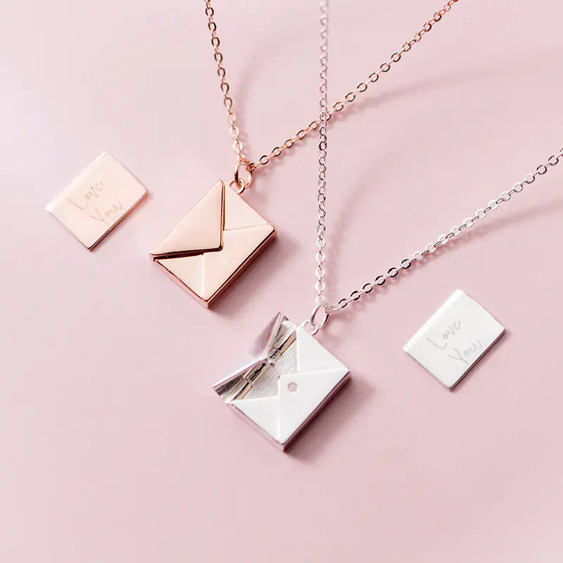 Two necklaces with square pendants on a pink background