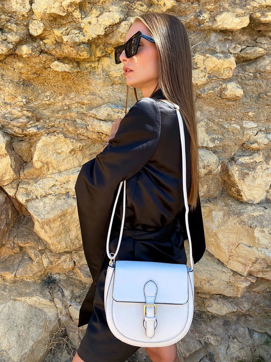 Woman with a light blue handbag against a stone wall