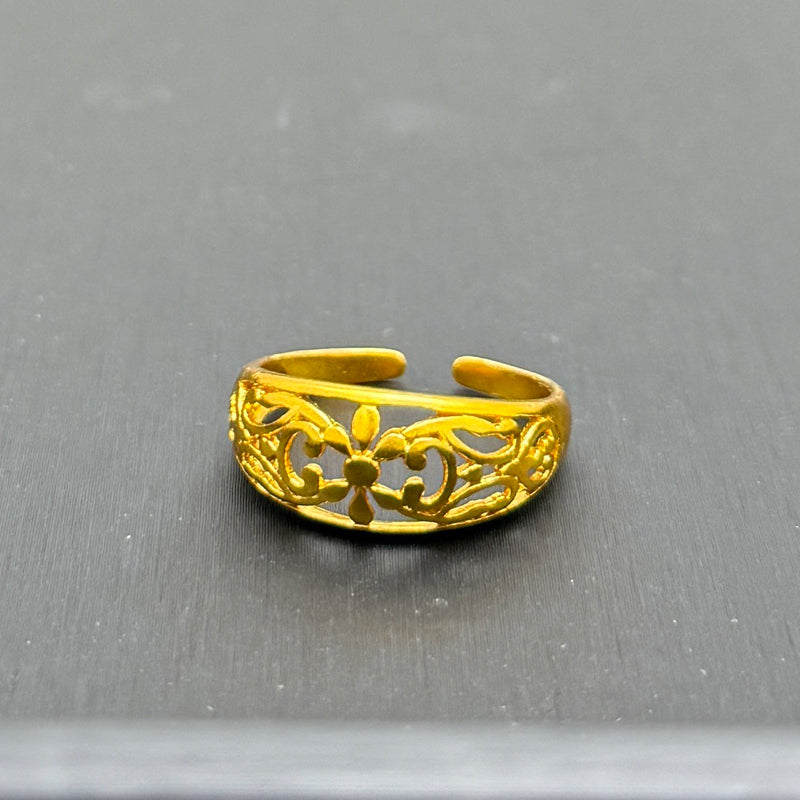 Gold ring with intricate design on a gray background