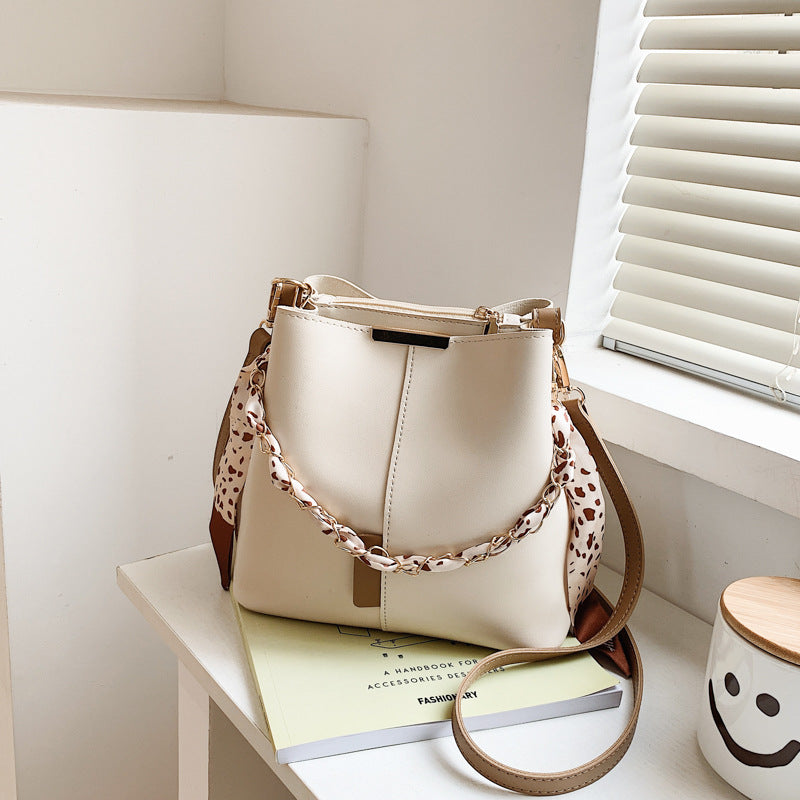 White handbag with a brown strap on a white surface